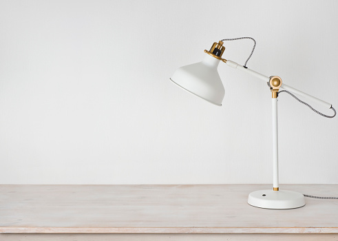 White lamp on wooden desk in room with copy space