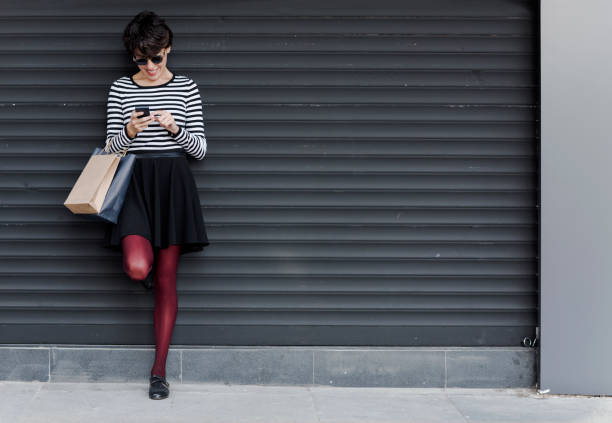 Smiling woman standing and looking at mobile phone