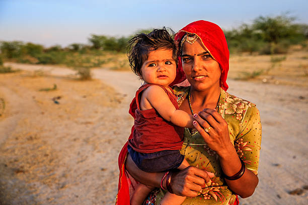 Young Indian woman holding her little baby, India Bishnois tribal woman holding her little baby, village near Jodhpur, Rajasthan. india poverty stock pictures, royalty-free photos & images