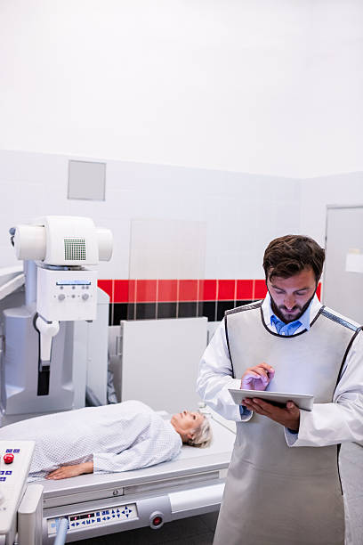 istock Doctor using digital tablet and patient lying on x 629761566