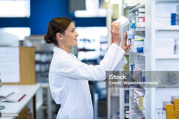 Pharmacist Checking Medicine In Shelf Stock Photo - Download Image Now - Pharmacist, Pharmacy, Medicine