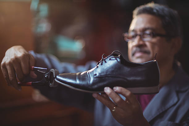 Shoemaker repairing a shoe Shoemaker repairing a shoe in workshop cobbler stock pictures, royalty-free photos & images