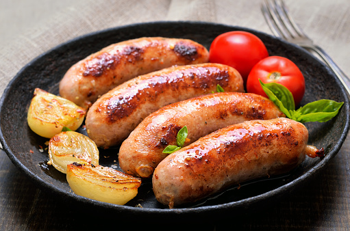 Grilled sausages and vegetables in frying pan, close up