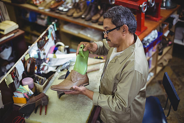 Shoemaker repairing a shoe sole Shoemaker repairing a shoe sole in workshop shoe mold stock pictures, royalty-free photos & images