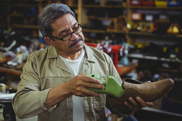 Shoemaker repairing a shoe sole Shoemaker repairing a shoe sole in workshop shoe mold stock pictures, royalty-free photos & images