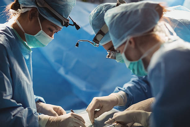 chirurgen, die im operationssaal operiert werden - chirurgenbrillen stock-fotos und bilder