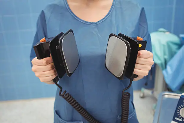 Mid section of female surgeon holding defibrillator at the hospital