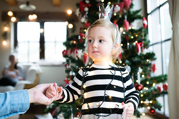 istock Father with daugter tangled in light chain at Christmas tree. 629767668