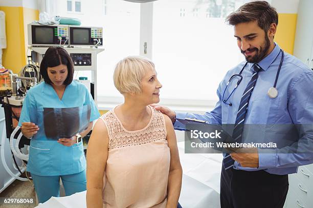 Male Doctor Interacting With A Patient While Nurse Stock Photo - Download Image Now - Casual Clothing, Doctor, Patient