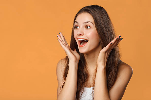 Surprised happy beautiful woman looking sideways in excitement. Isolated Surprised happy beautiful woman looking sideways in excitement. Isolated on orange background disbelief stock pictures, royalty-free photos & images