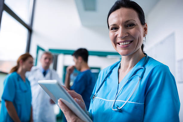 istock Portrait of smiling surgeon using digital tablet in corridor 629772154
