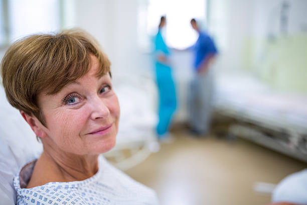 Portrait of smiling patient sitting on bed Portrait of smiling patient sitting on bed in hospital spinal surgery recovery stock pictures, royalty-free photos & images