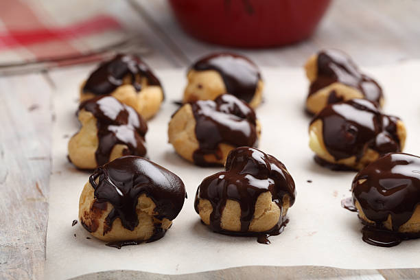 profiteroles glaseados con chocolate - chocolate pot de creme fotografías e imágenes de stock