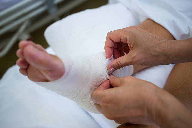 Doctor bandaging patients leg Doctor bandaging patients leg in hospital bandage stock pictures, royalty-free photos & images