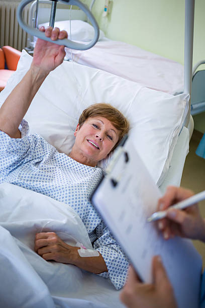istock Patient lying on bed while nurse writing on clipboard 629778160