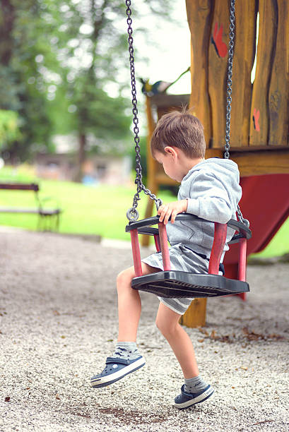 istock Cute Lonely Boy on Playground Swing 629778302