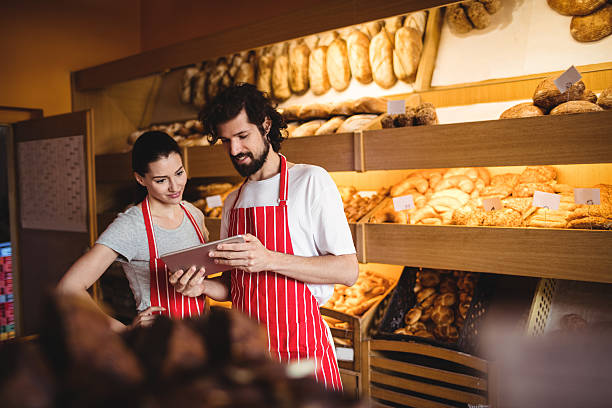 Couple using digital tablet Couple using digital tablet in bakery shop baker occupation stock pictures, royalty-free photos & images