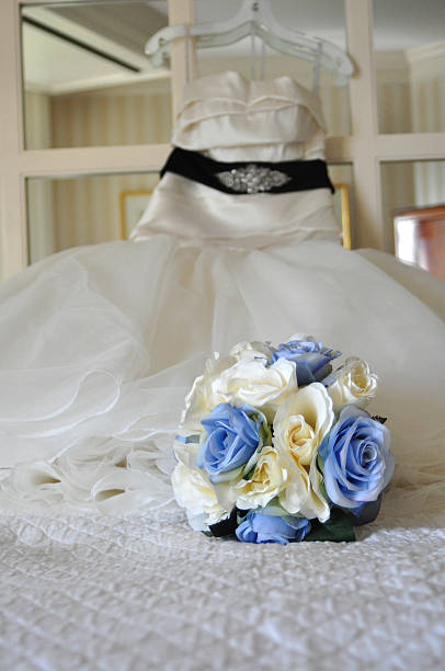 istock Bride Bouquet on Bed with Wedding Dress Hanging on Mirror 629780602