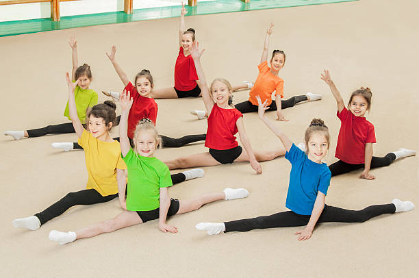 glückliche aktive kinder im fitnessstudio - the splits flexibility yoga teenage girls stock-fotos und bilder