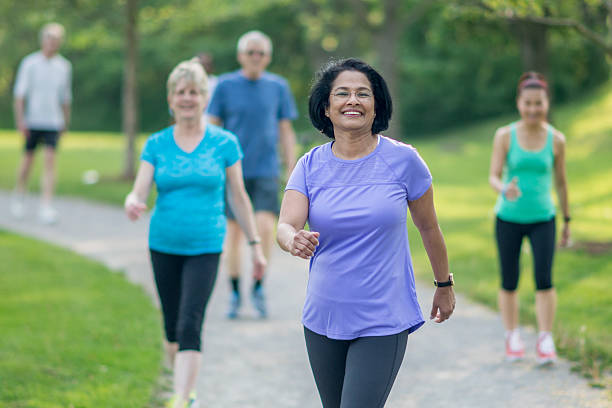 Seniors Walking at the Park A multi-ethnic group of senior adults are walking together through the park on a sunny day. someone walking sneakers stock pictures, royalty-free photos & images