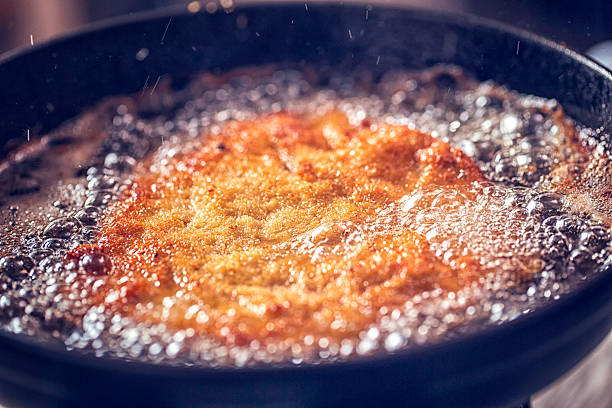 freír wiener schnitzel en aceite profundo en una sartén - viennese schnitzel fotografías e imágenes de stock