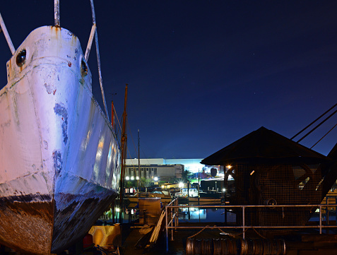 An old boat and crane at the Riverside Quay on the Isle of Wight with industrial estate behind.