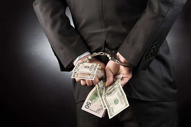 Businessman is arrested and handcuffed with dollar Businessman is arrested and handcuffed with dollar high quality and high resolution studio shoot white collar crime handcuffs stock pictures, royalty-free photos & images