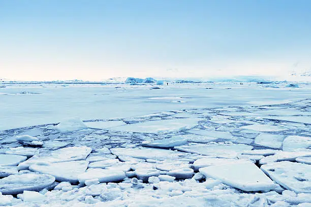 Landscape at the lagoon in winter.Some tourists are walking on the ice of the lake.