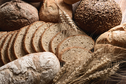 composition of different breads and ears of corn on the wooden background