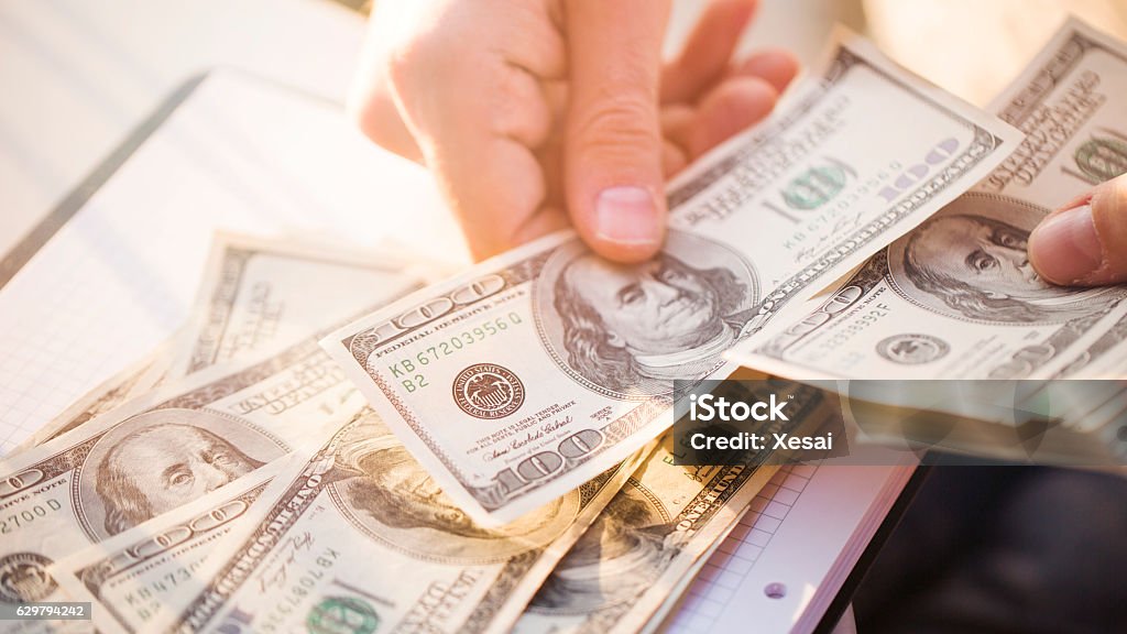 Hands counting us dollars with calculator and digital tablet Currency Stock Photo