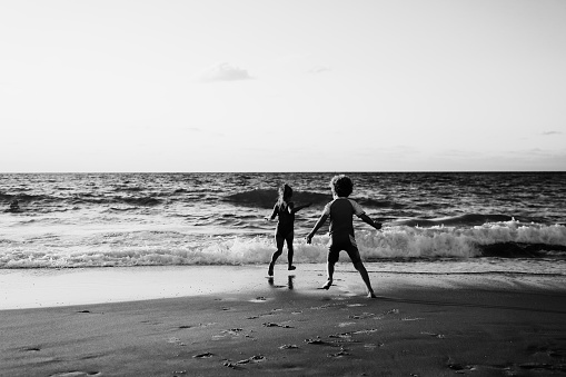 kids playing on the beach at sunset. Black and white photo.