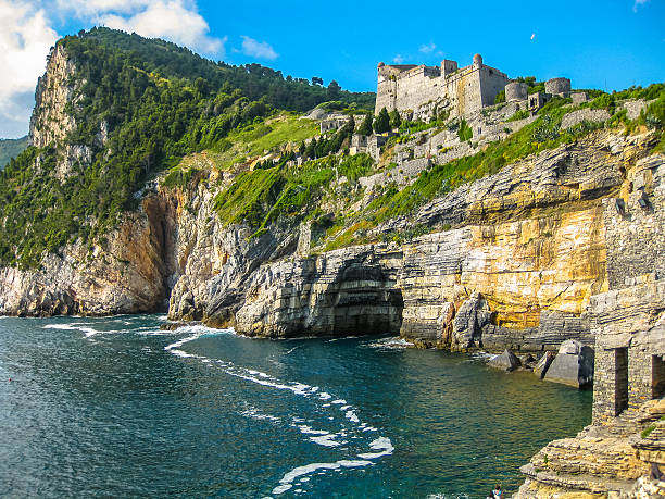 Portovenere, the Byron Cave, beautiful shoreline scenery of Cinque Terre, Ligurian Coast, La Spezia, Italy. On background the Doria Castle that dominates the promontory.