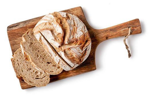 freshly baked bread on wooden cutting board isolated on white background, top view