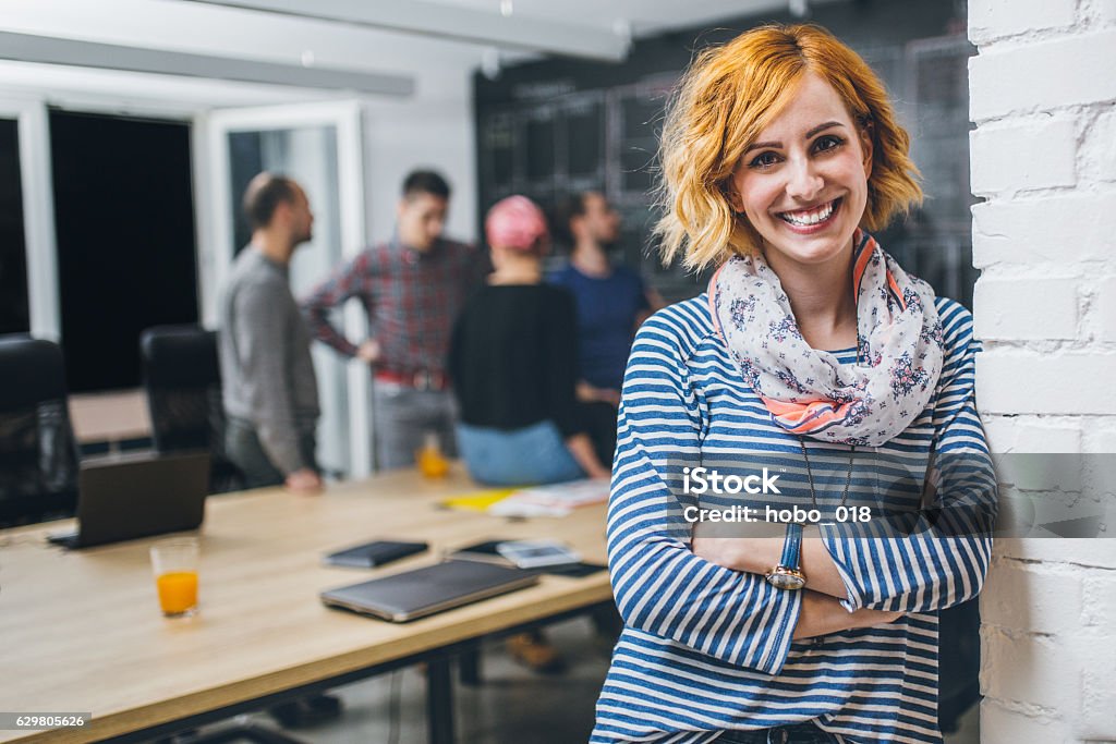 Photo of young business woman in a conference room Photo of young business woman in a conference room, with a group of coworkers in backside Education Training Class Stock Photo