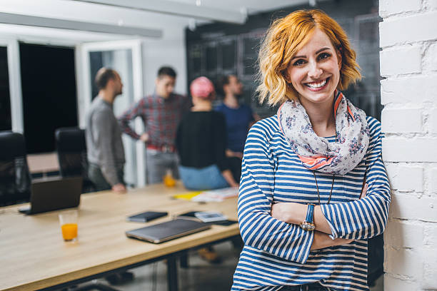 Photo of young business woman in a conference room Photo of young business woman in a conference room, with a group of coworkers in backside redhead photos stock pictures, royalty-free photos & images