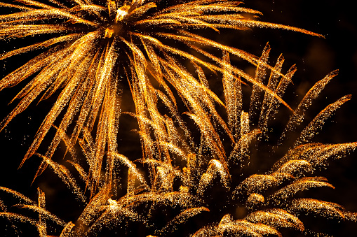 An impressive display of fireworks on Umm Suqeim Beach in Dubai in the United Arab Emirates, to bring in the New Year. Streaks of gold, against the darkness of the skies, light up the night sky in the climax to the celebration, bringing in the New Year. A long exposure, captures the image against the dark sky. Horizontal format.