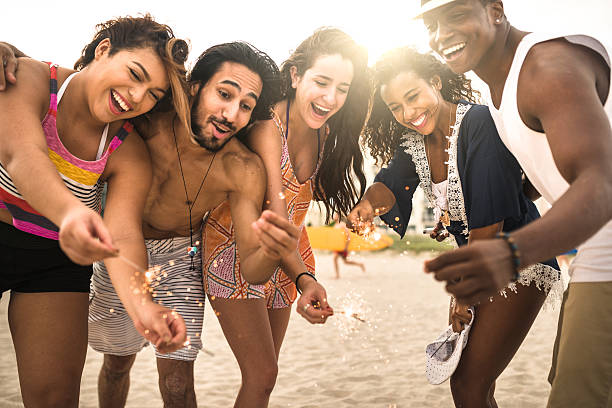 istock friends using a sparkler togetherness on the beach 629808310