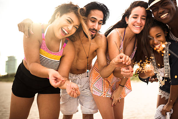 istock friends using a sparkler togetherness on the beach 629808488