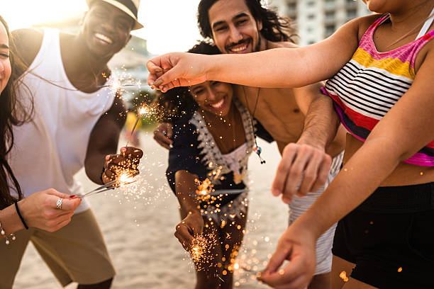 istock friends using a sparkler togetherness on the beach 629808638