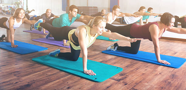 adultes ayant un cours de yoga dans un club de sport - yoga class caucasian young adult group of people photos et images de collection