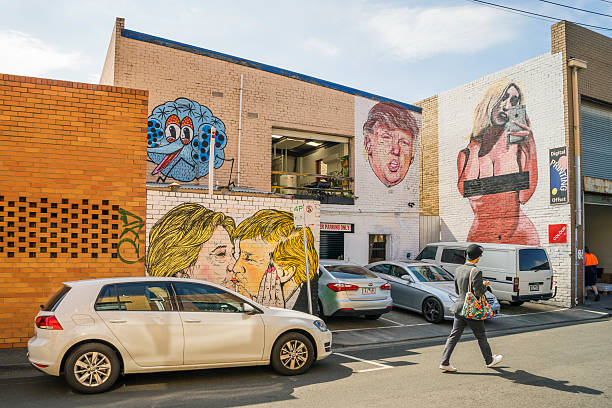 Melbourne, Australia - December 16, 2016: A man walks past an industrial warehouse on Gwynne St, Cremorne, which has been covered in murals depicting Hillary Clinton, Donald Trump and Kim Kardashian.