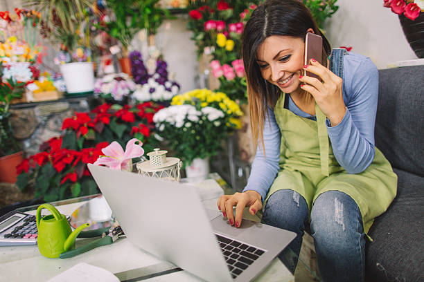 fiorista che prende ordini al telefono - fioraio negoziante foto e immagini stock