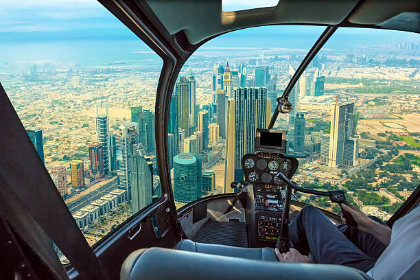 Helicopter in Dubai Downtown Helicopter cockpit flies in skyscrapers of Dubai downtown skyline on Sheikh Zayed Road, United Arab Emirates, with pilot arm and control board inside the cabin. helicopter modern stock pictures, royalty-free photos & images