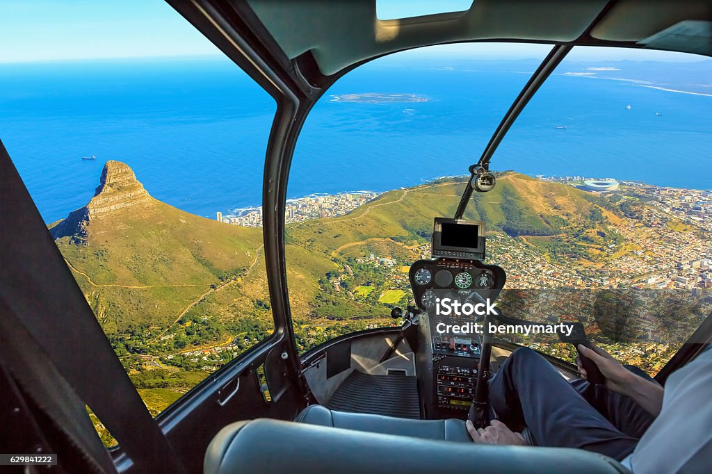 Scenic flight Cape Town Helicopter cockpit flies in Lion's Head, coast and Cape Town in South Africa, with pilot arm and control board inside the cabin. Helicopter Stock Photo
