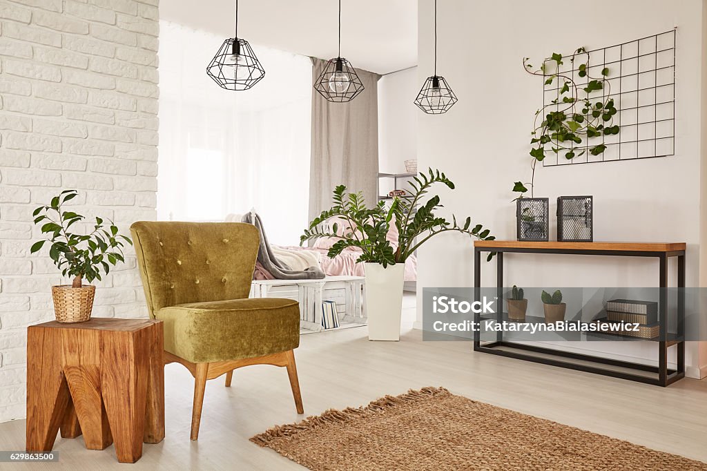 Room with green armchair White room with green armchair and wooden side table Illuminated Stock Photo