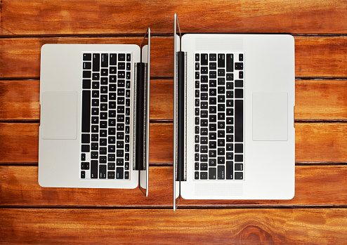 Two modern laptops on wooden table view from top