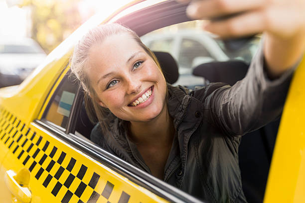 istock Smiling woman taking selfie while sitting in taxi 629866566