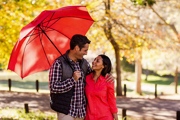 istock Couple holding umbrella at park 629866616