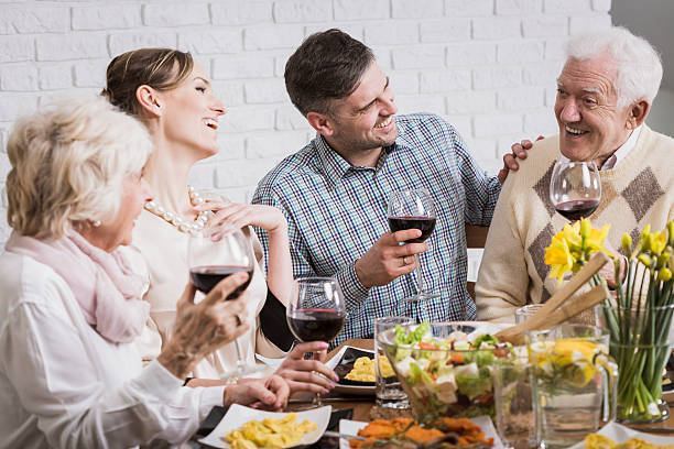 Laughing family during dinner Laughing members of the family holding glasses of wine during dinner father in law stock pictures, royalty-free photos & images