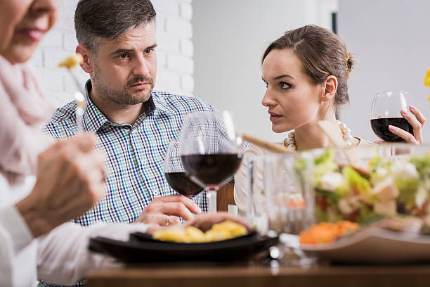 Couple arguing during family dinner Young elegant couple arguing during sunday family dinner father in law stock pictures, royalty-free photos & images